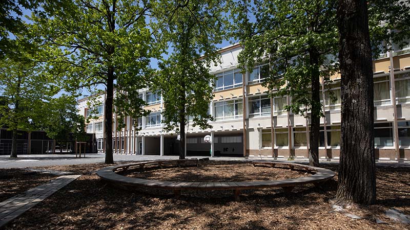 Côté maternelle, la cour est séparée en deux zones. D’un côté, la cour nature avec tables et chaises dans l’herbe. De l’autre, une cour avec des structures de jeux existantes.